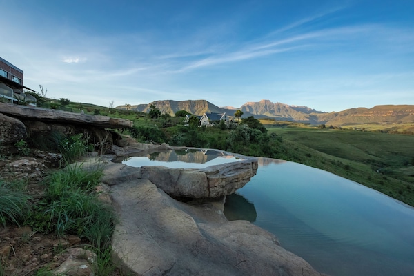 Una piscina techada, una piscina al aire libre, sombrillas