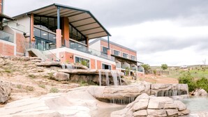 A modern building with a waterfall feature in front. - Dragonview Lodge (Cathkin Park)