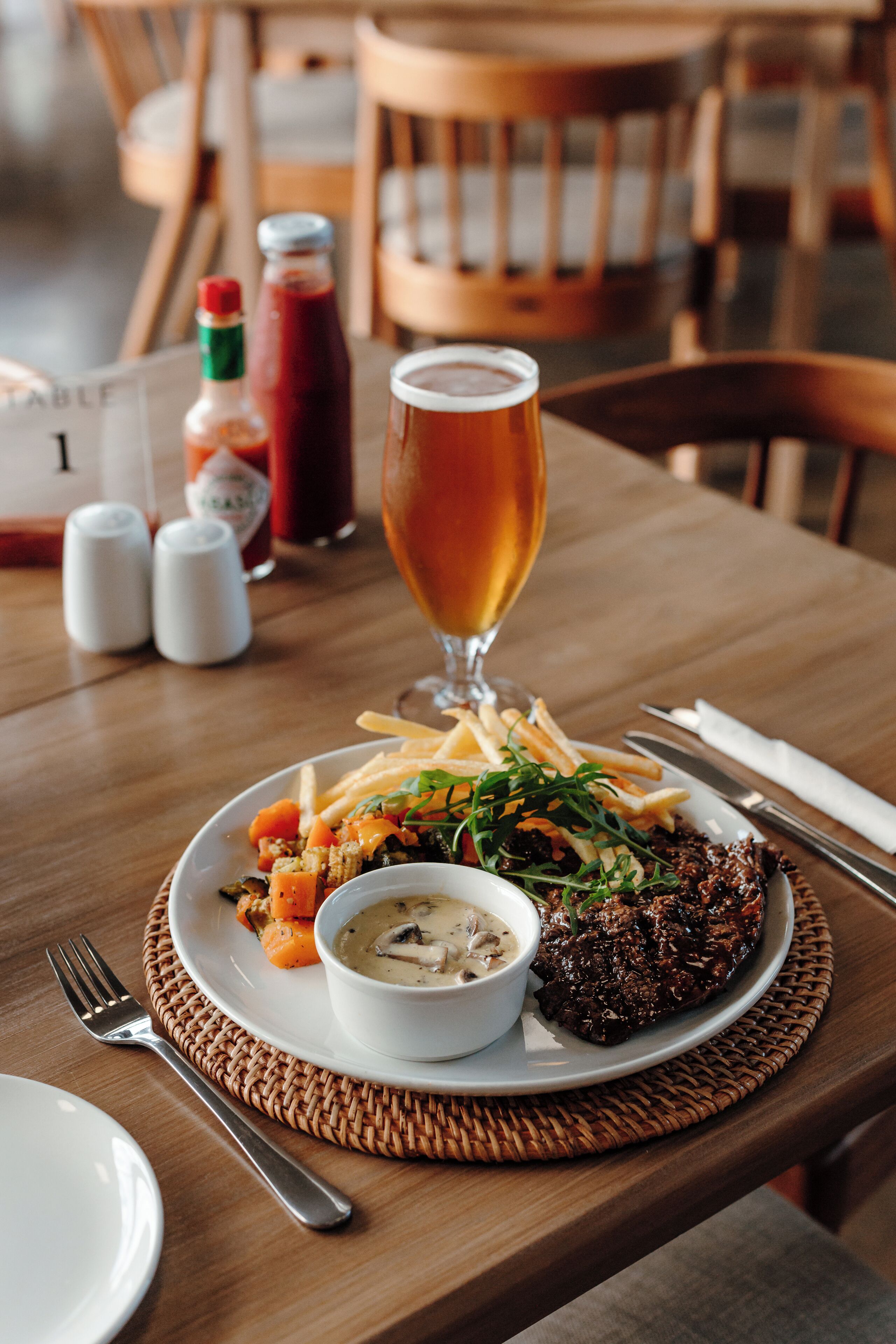 Ein Esstisch mit einem Teller Essen, einem Bierglas und Gewürzen.
