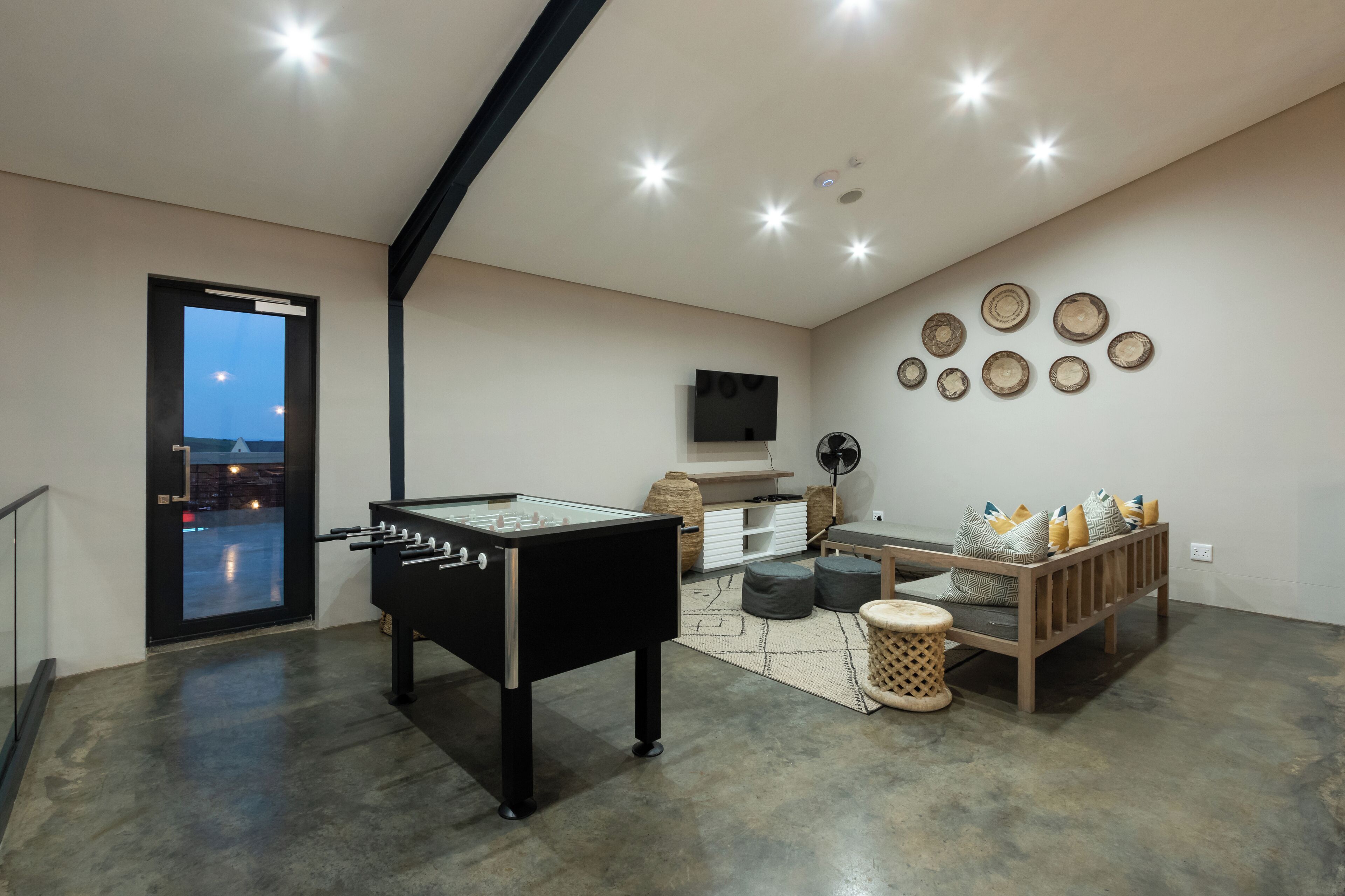 A modern living room with a foosball table, a sofa, and a TV mounted on the wall.