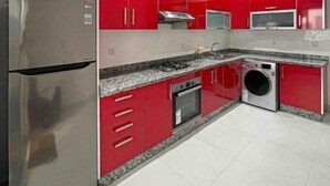 A modern kitchen with red cabinets, stainless steel appliances, and a granite countertop.