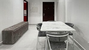 A modern dining area with a rectangular table and four chairs, a bench along one wall, and a dark door in the background.