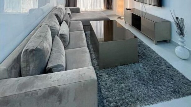 A modern living room with a sectional sofa, a flat-screen TV, and a minimalist design.