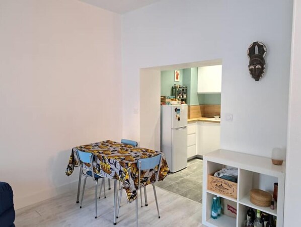 Cozy living space with a dining area, kitchenette, and shelf unit.