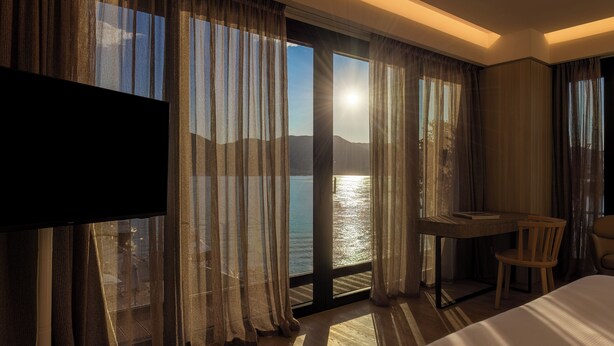 Una habitación de hotel con un ventanal grande, un escritorio, una silla y una cama.