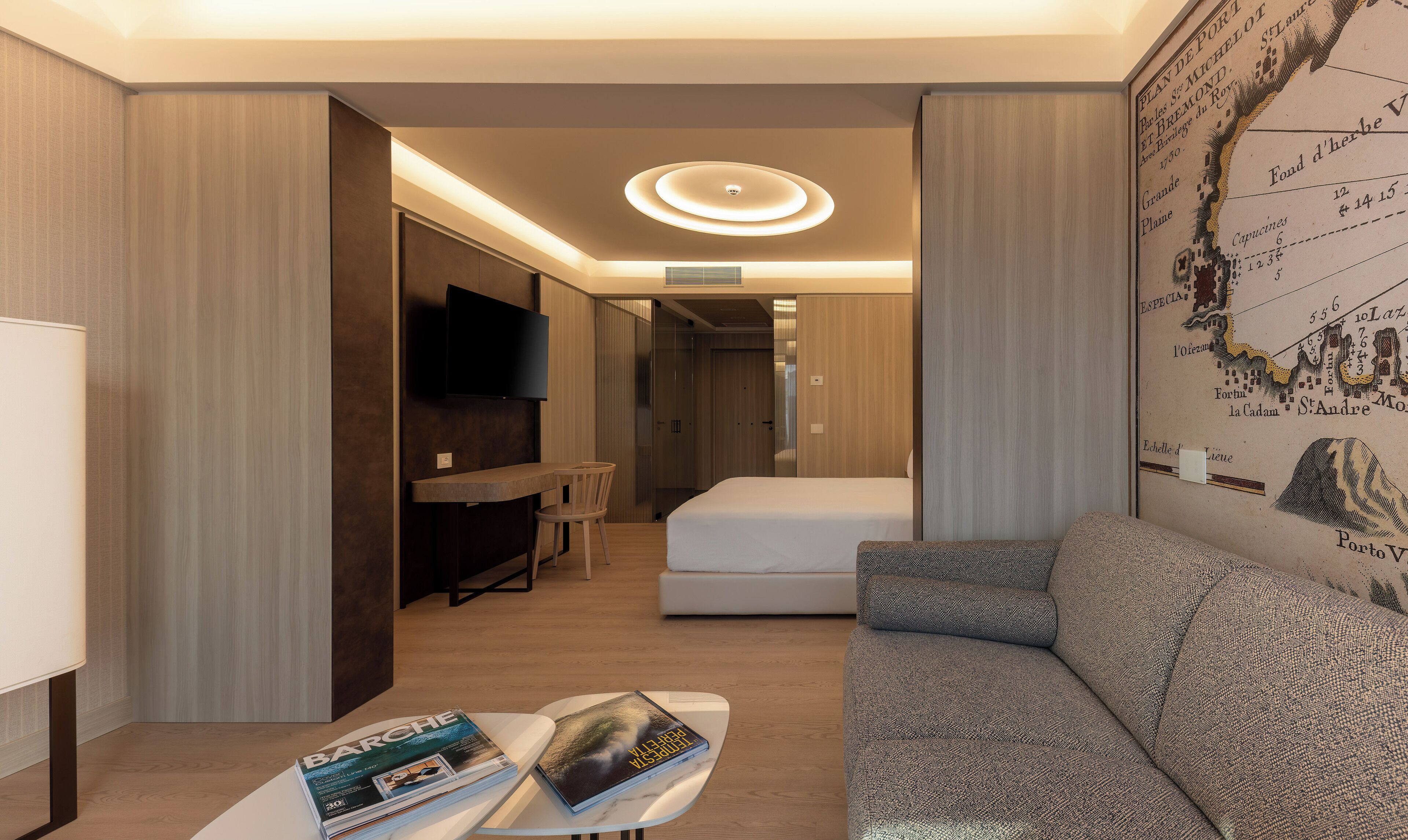 A modern hotel room with a flat-screen TV, a sofa, a bed, and a dining table.