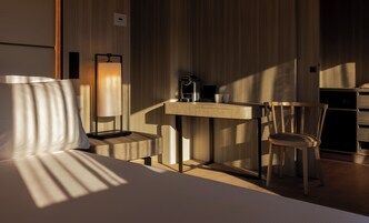 Una habitación de hotel moderna con un escritorio de madera, una silla, una lámpara y una cama.