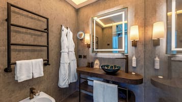 A modern bathroom with a large mirror, a sink, a bidet, and towel racks.