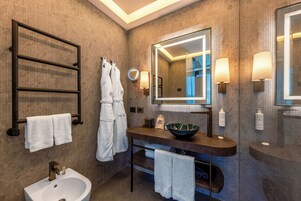 Un baño moderno con un espejo grande, un lavamanos, un bidé y toalleros.