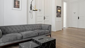 A modern hotel room with a grey sofa, a marble coffee table, and a wall-mounted lamp. - Nest Boutique Hostel (Bucharest)