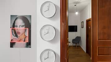Un pasillo con una puerta de madera, una silla negra y un televisor montado en la pared.