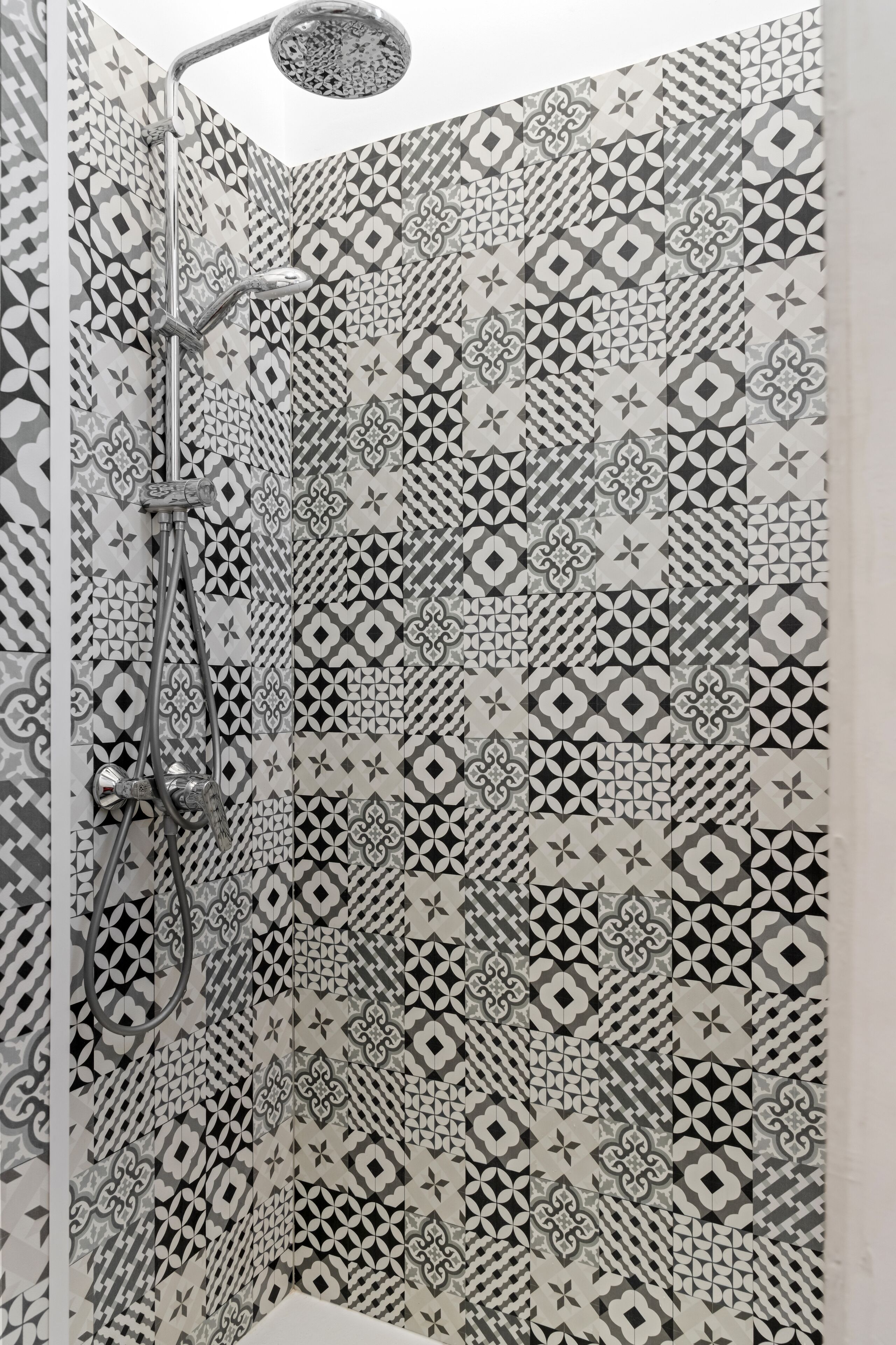 Ducha con un diseño de azulejos geométricos y cabezal de ducha de mano.