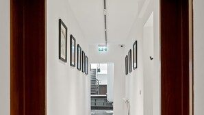 A hallway with wooden doors, framed pictures on the walls, and a staircase at the end. - Nest Boutique Hostel (Bucharest)