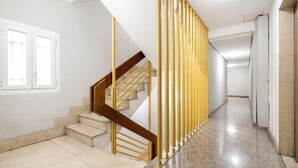 A staircase with a wooden handrail and a yellow safety barrier, leading to a landing with a white door. - Estudio Encantador Plaza España (Madrid)