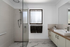 Un baño moderno con ducha, lavabo y espejo.