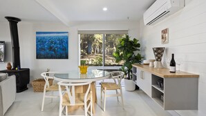 A modern kitchen with a dining area, large windows, and a view of the outdoors.