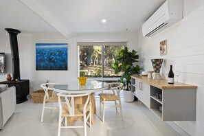 Una cocina moderna con comedor, que cuenta con un amplio ventanal, una estufa negra y un refrigerador blanco.