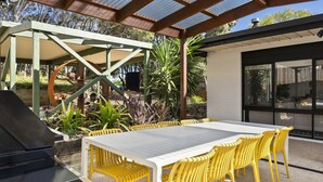 An outdoor patio with a grill, yellow chairs, and a table.
