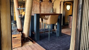 Un coin repas rustique avec une table et des chaises en bois, un luminaire suspendu et un plafond en bois.