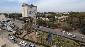 A multi-story hotel with a modern design, surrounded by a landscaped area with trees and a small park. - Hotel Casa Royal (Amritsar)