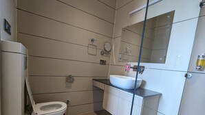 A modern bathroom with a toilet, sink, and mirror. - Hotel Casa Royal (Amritsar)
