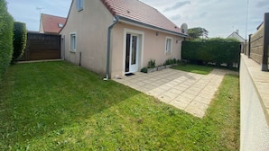 A single-story house with a tiled patio, a front door, and a small front yard.