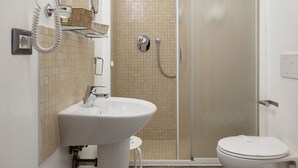 Une salle de bain équipée d’un lavabo, d’un miroir, d’un sèche-cheveux et d’une cabine de douche.