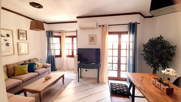 Una sala de estar con sofá, mesa de centro, televisor y una mesa de comedor con sillas.