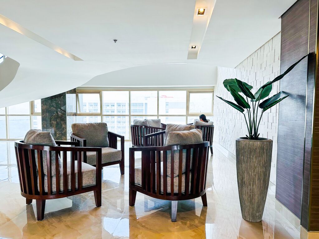 A spacious lobby with modern furniture, large windows, and a large potted plant.