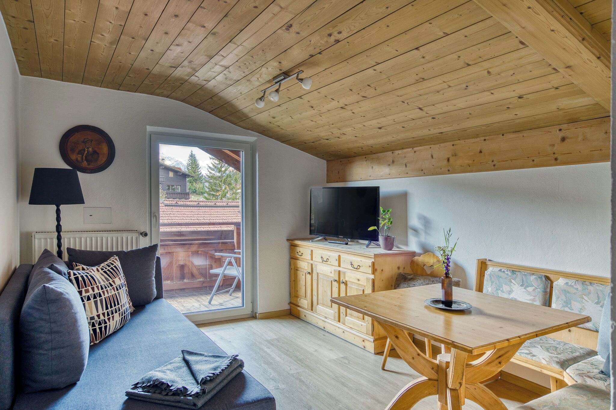 Een gezellige woonkamer met een bank, een televisie, houten kasten en een eettafel.