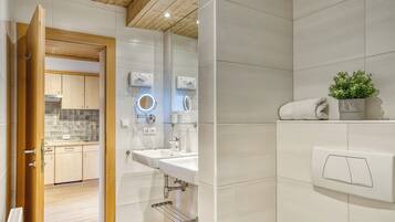 A modern bathroom with a white sink, a mirror, and a towel rack.
