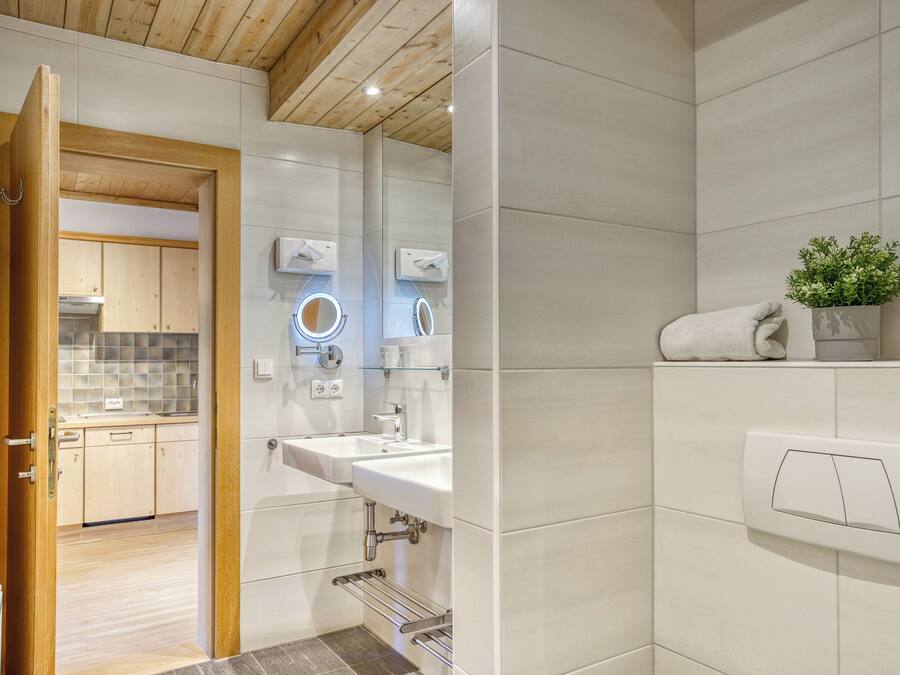 A modern bathroom with a white sink, a mirror, and a towel rack.