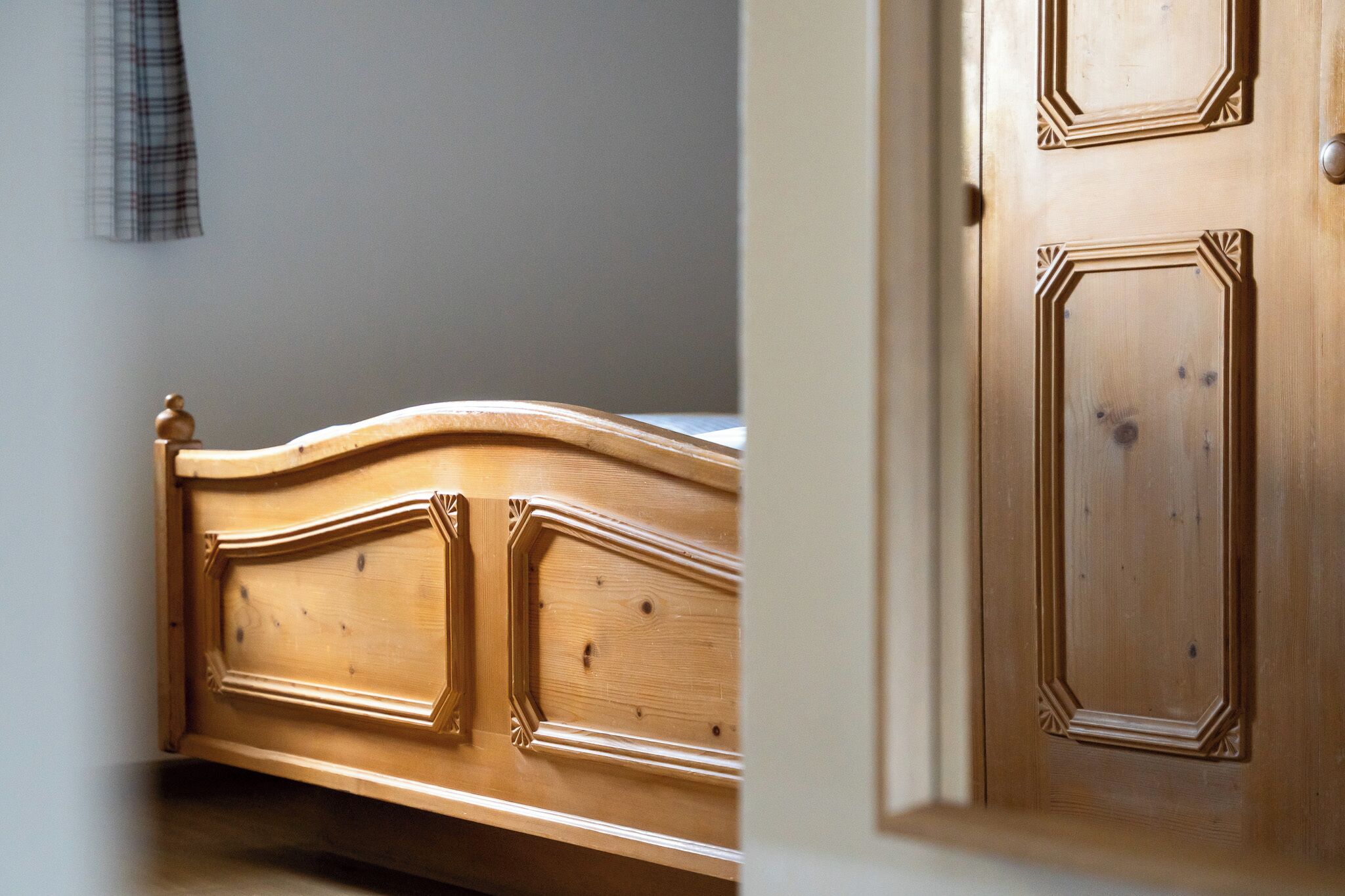 Un lit en bois doté d’une tête de lit incurvée et d’une porte ornée de panneaux décoratifs.