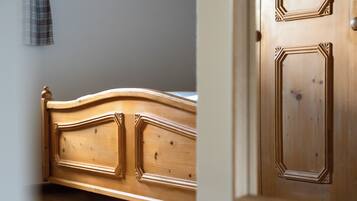 Un lit en bois doté d’une tête de lit incurvée et d’une porte ornée de panneaux décoratifs.