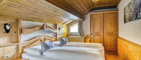 Un dormitorio de madera con una cama grande, cabecera de madera y una ventana con cortinas.