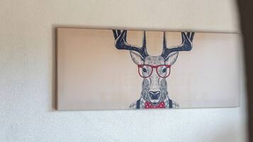 Ein modernes Wohnzimmer mit einem grauen Sofa und einem gerahmten Kunstwerk, das einen Hirsch mit Brille zeigt.