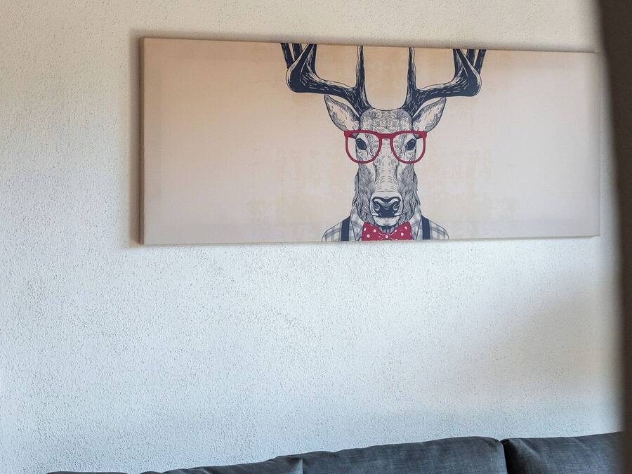 Ein modernes Wohnzimmer mit einem grauen Sofa und einem gerahmten Kunstwerk, das einen Hirsch mit Brille zeigt.