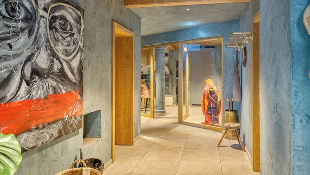 A hallway with a large abstract painting, a wooden ceiling, and a view into another room with a colorful artwork. - Boutiquehotel ZOMM in Seefeld (Seefeld in Tirol)