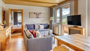 A cozy living room with a sofa, a TV, and a wooden table. - Boutiquehotel ZOMM in Seefeld (Seefeld in Tirol)