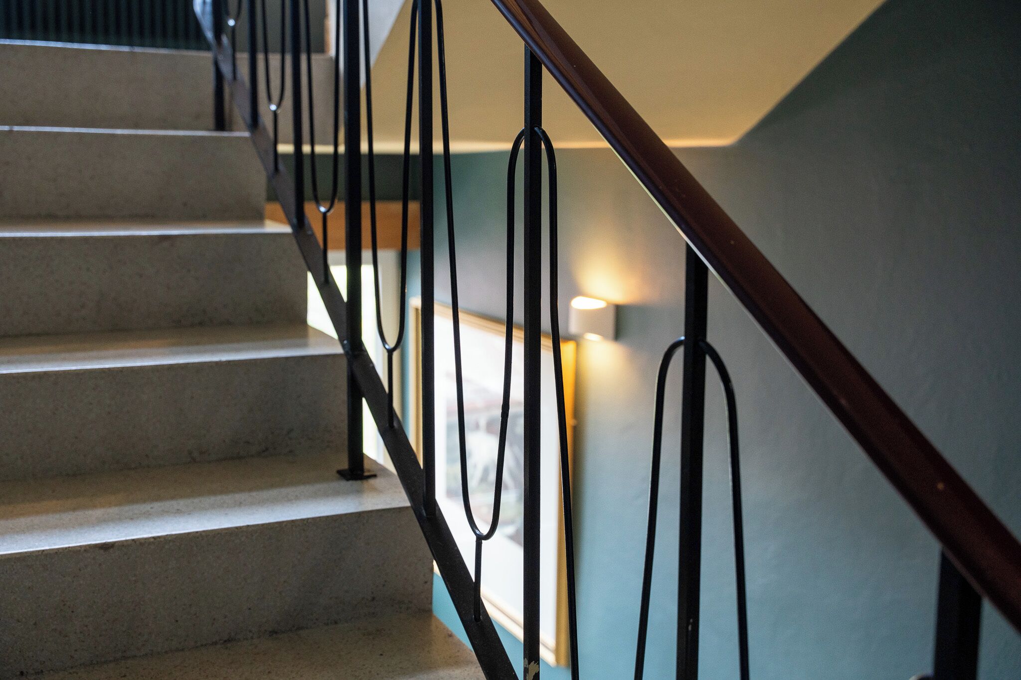 Una escalera con barandilla de madera y balaustres de metal negro.