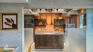 A modern kitchen with pendant lighting, a central island, and a dining area with a table and chairs. - Boutiquehotel ZOMM in Seefeld (Seefeld in Tirol)