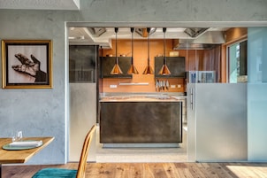 Una cocina moderna con iluminación colgante, una isla central y una zona de comedor con mesa y sillas.