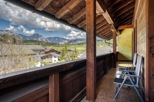 Un balcone in legno con vista su montagne e un villaggio.