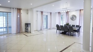 A spacious, well-lit room with a large dining table, modern decor, and large windows offering natural light.