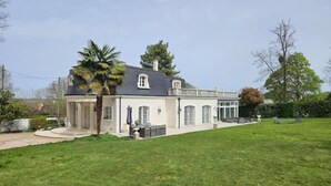 A two-story house with a covered patio and a lawn.