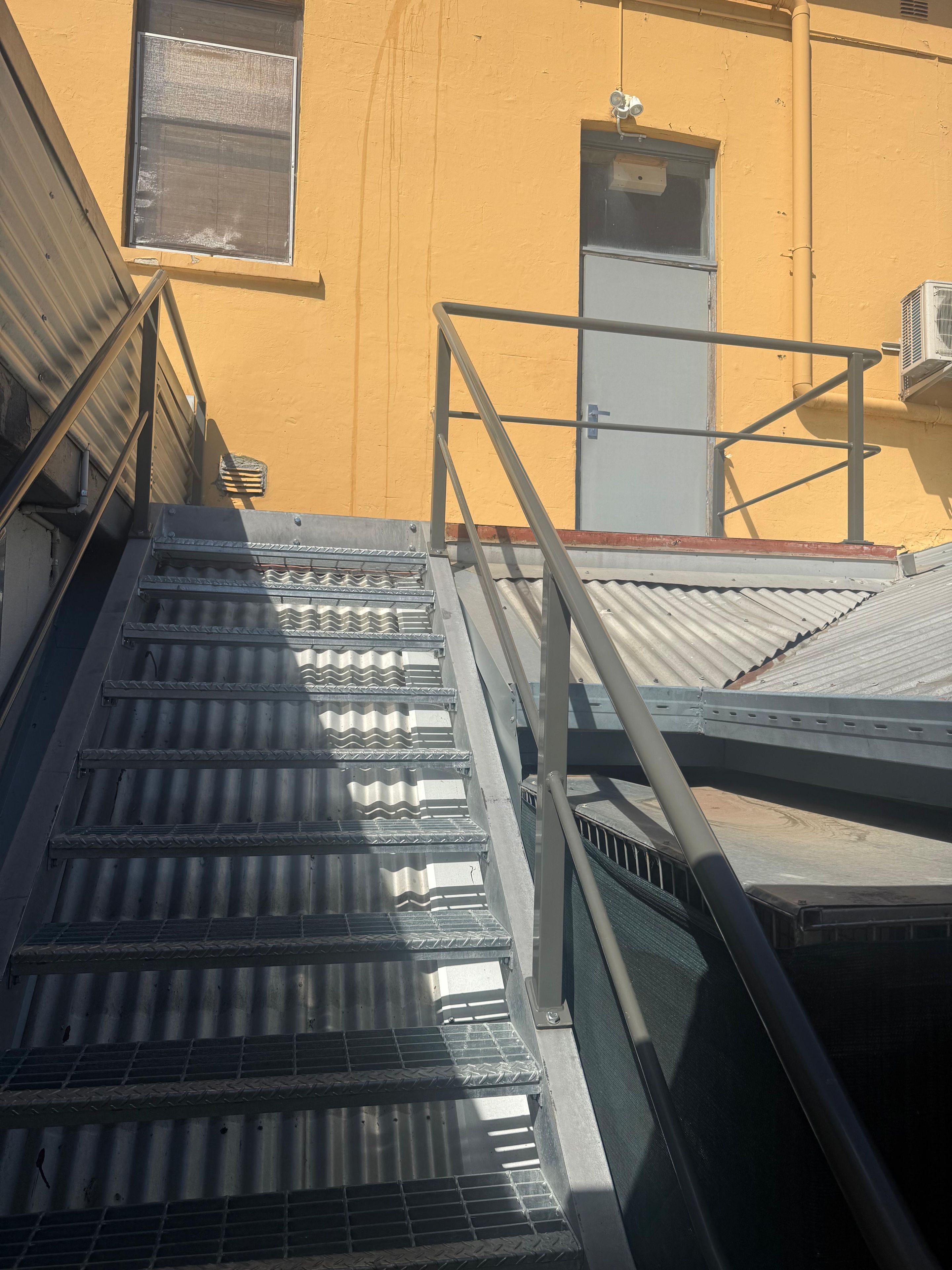 Un escalier métallique doté de rampes mène à l’entrée d’un immeuble.