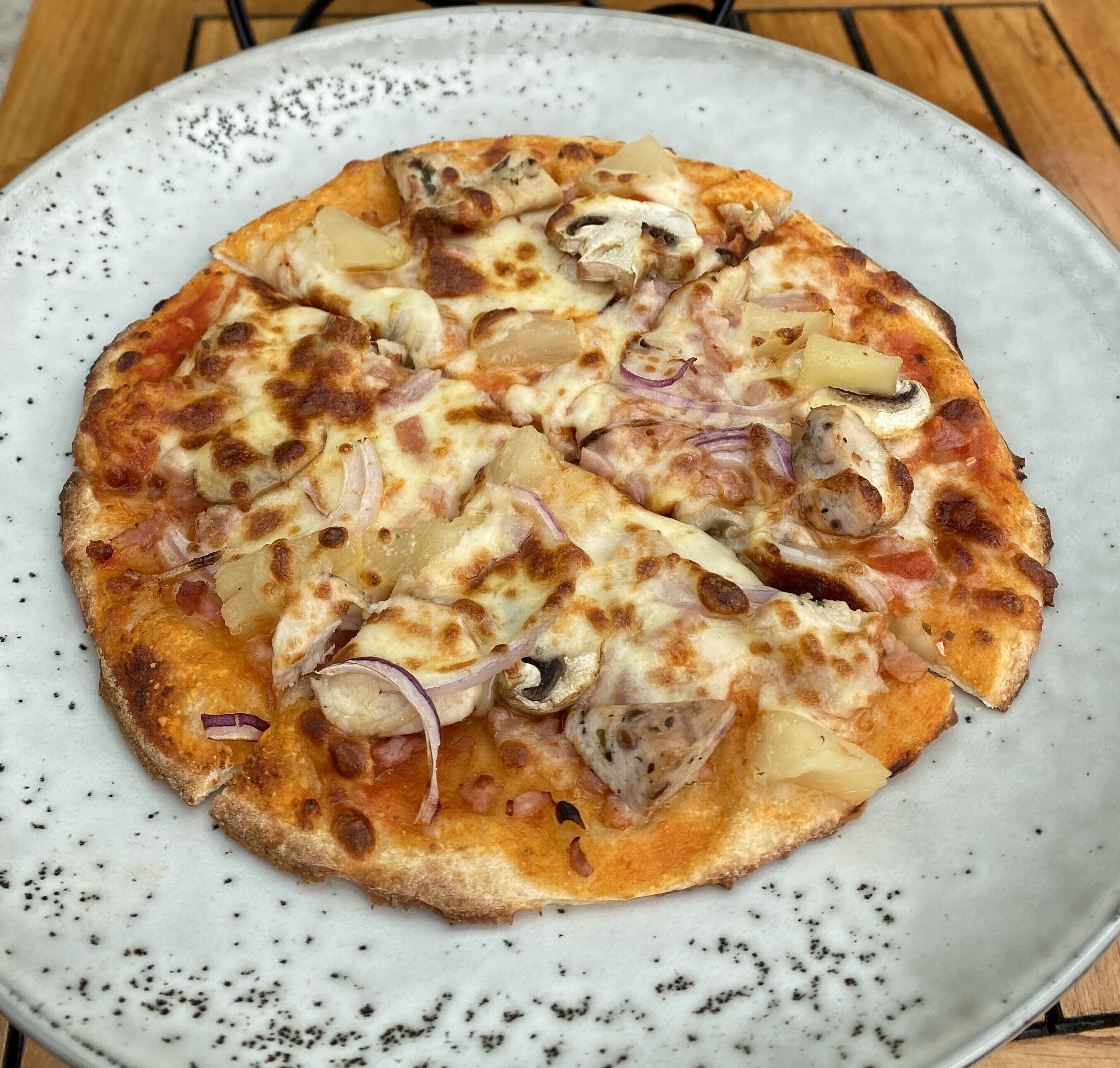 En pizza med olika ingredienser ovanpå, serverad på en vit tallrik.
