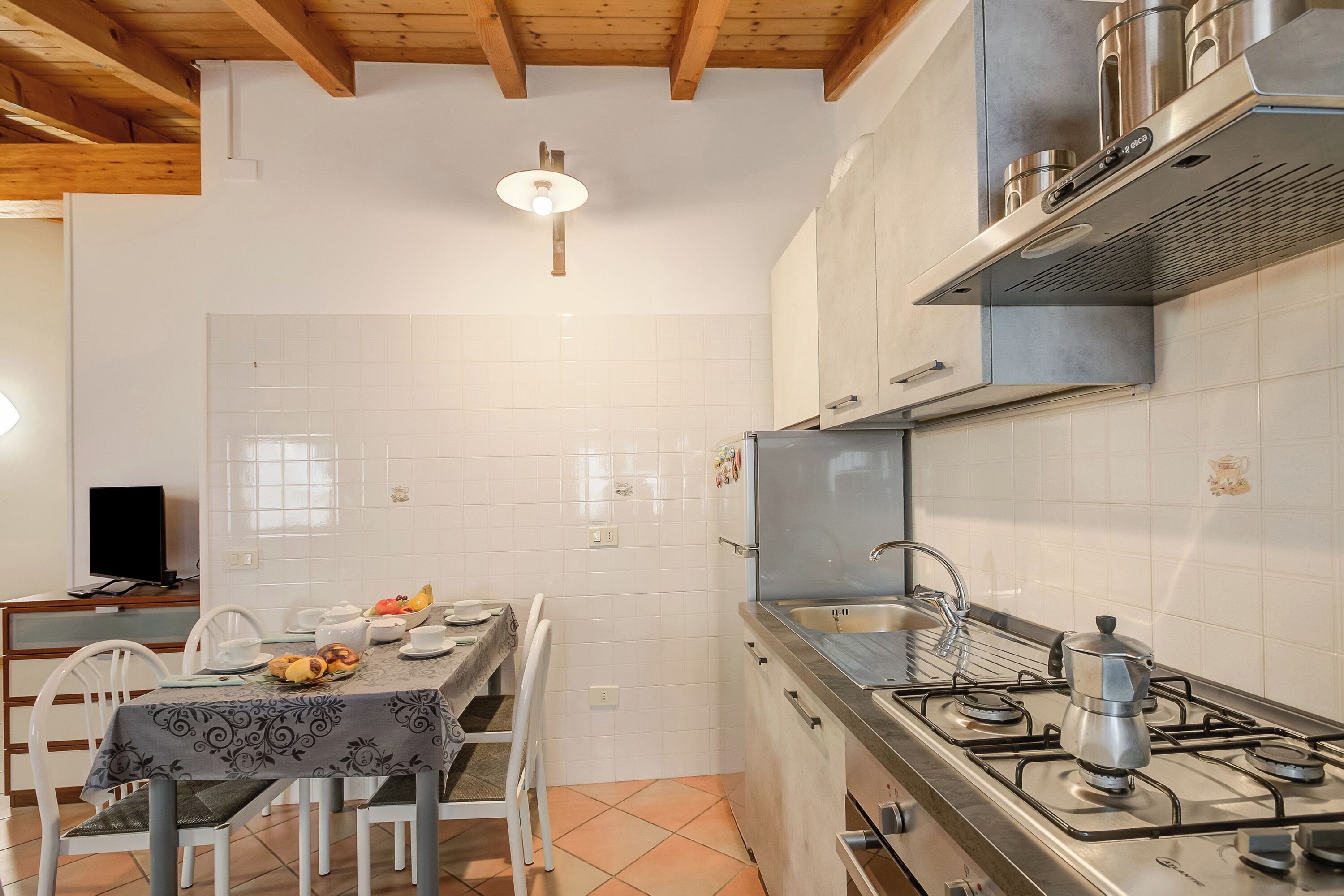A kitchen with a gas stove, a sink, and a dining area with chairs and a table.