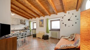 Un espacio habitable compacto con cocina, comedor, cama y un reloj de pared.