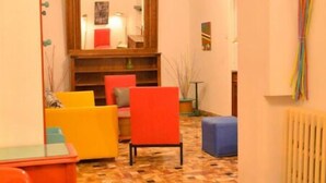 Una sala de estar acogedora con piso estampado, un espejo grande y sillas coloridas.